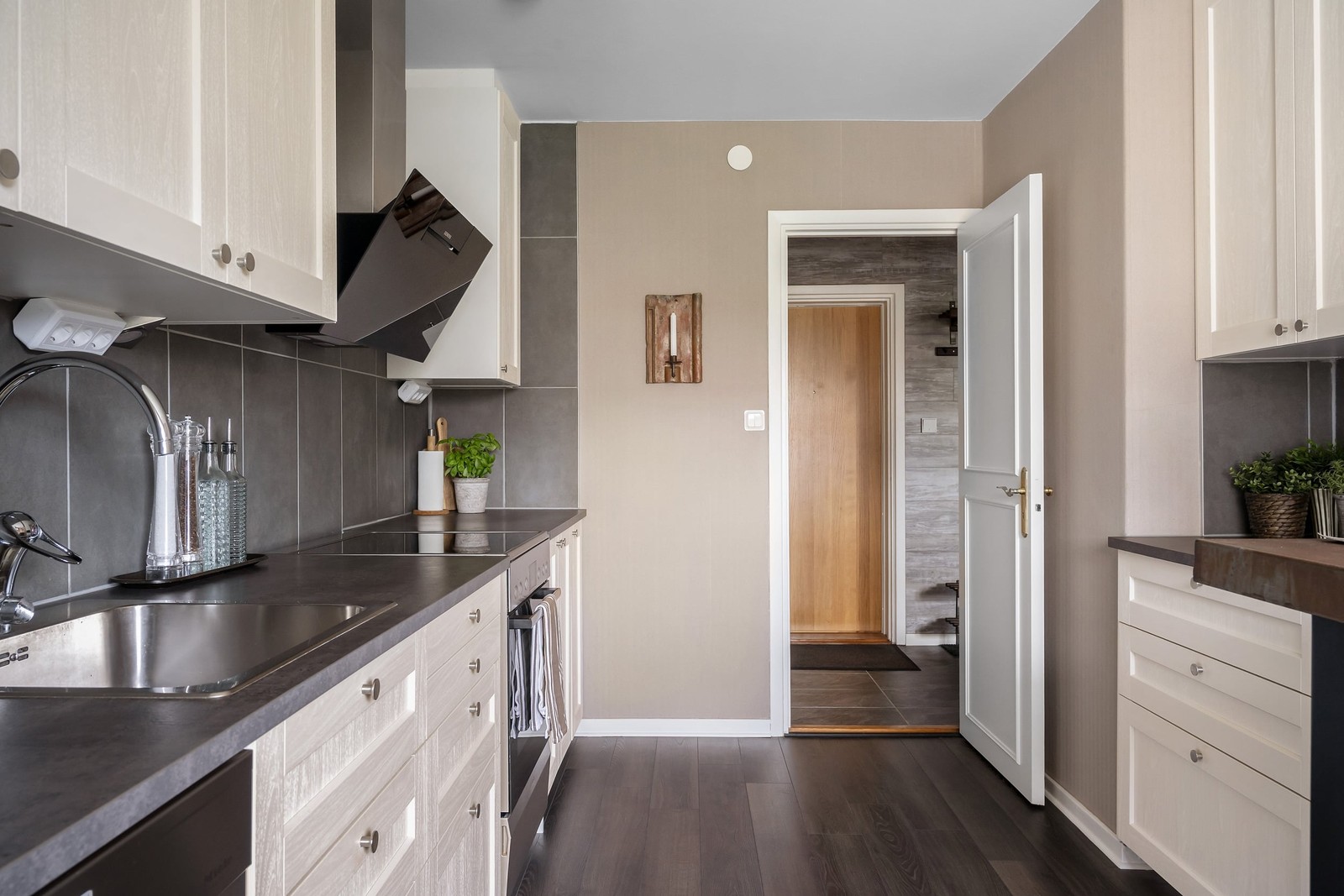 Smakfullt vitt kök med moderna materialval och plats för matbord vid fönstret.