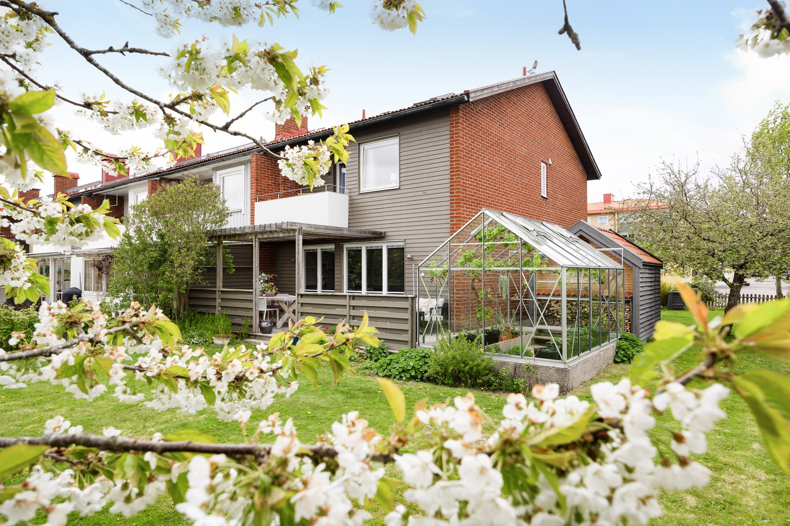 Stor hörntomt med fruktträd, växthus och isolerat förråd