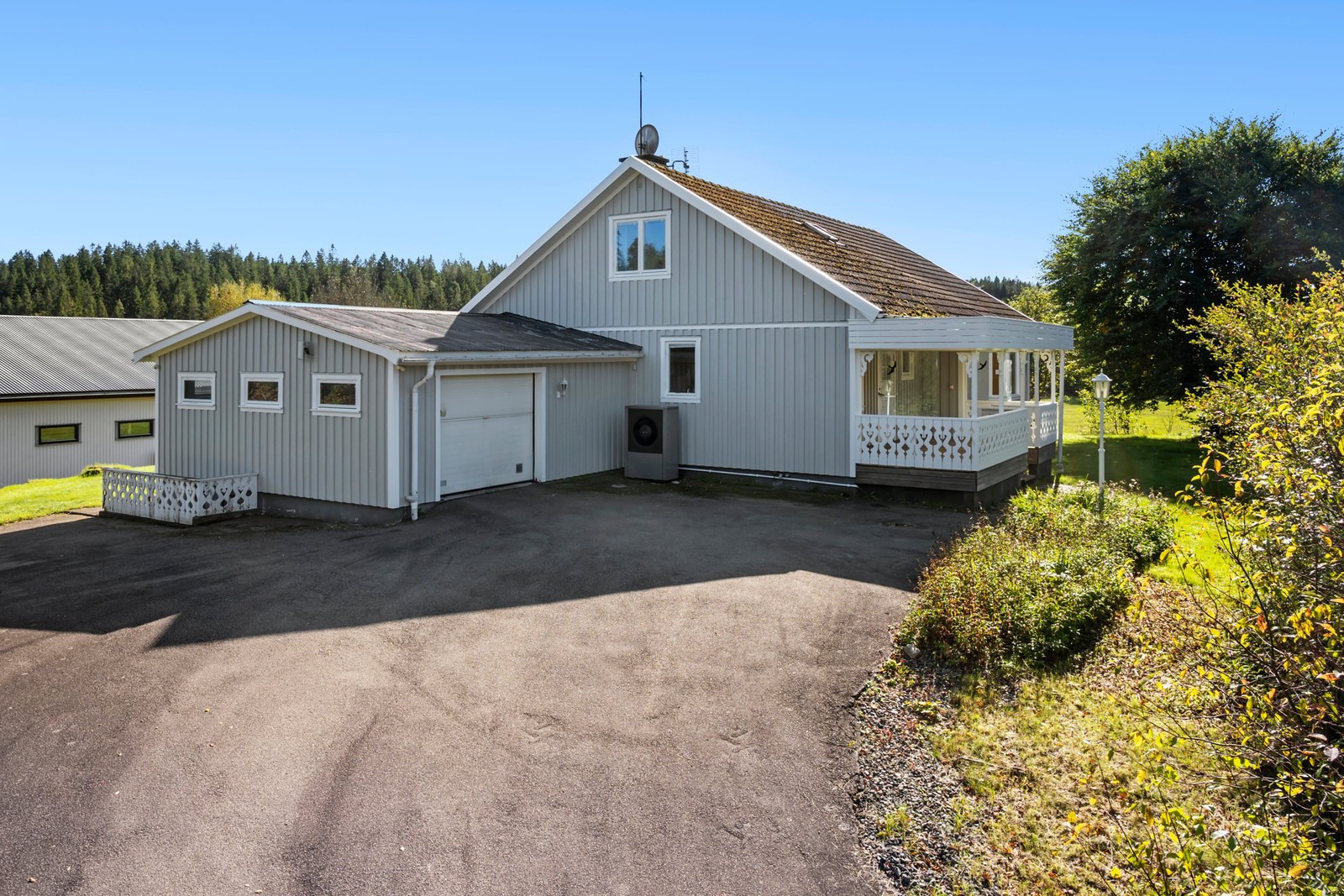 Klassisk villa med garage, veranda och generösa ytor framför huset.