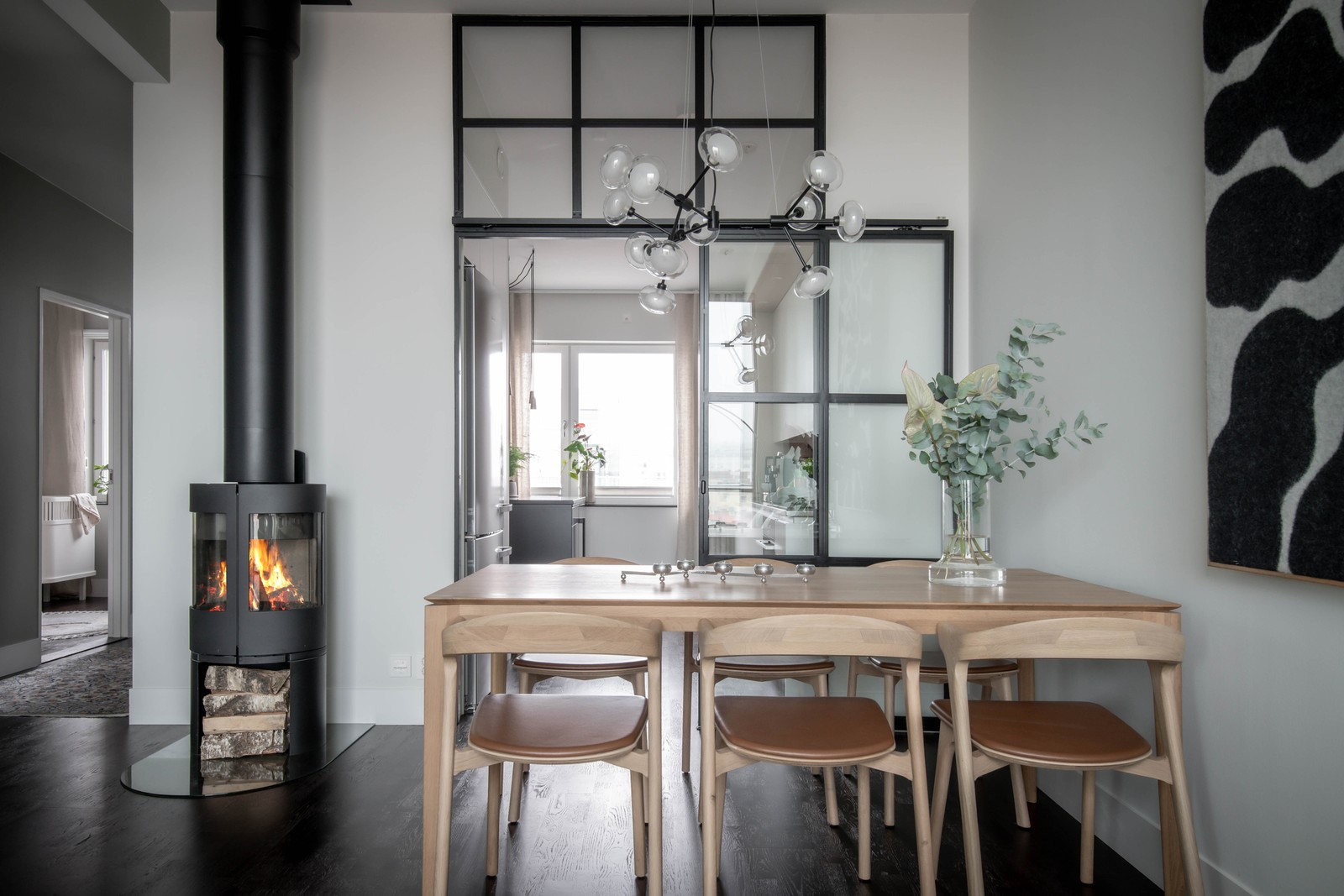 Matsalen med värmande braskamin och industriglas mot köket