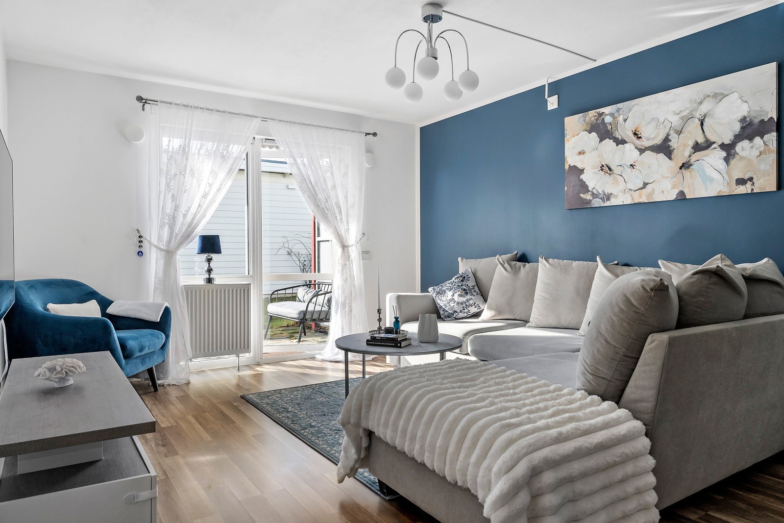 Ljust och inbjudande vardagsrum med smakfull fondvägg och plats för större soffgrupp.