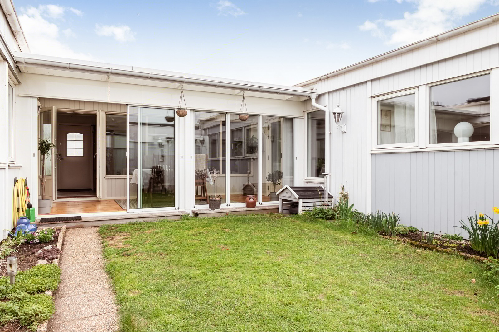 Helt privat atriumgård med liten gräsmatta och fina blommor