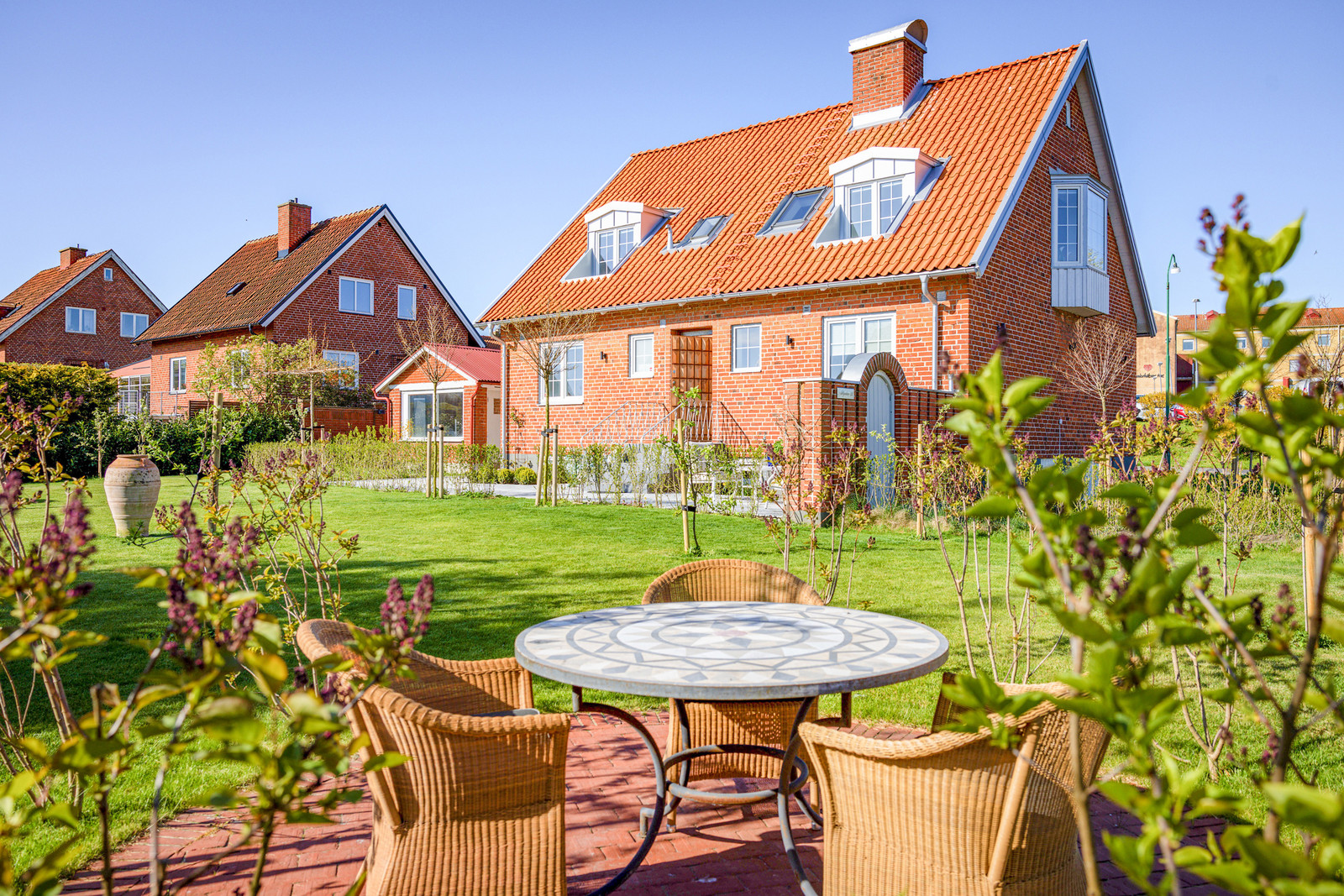 Nyanlagd trädgård med planteringar, stensättningar och isolerat orangeri