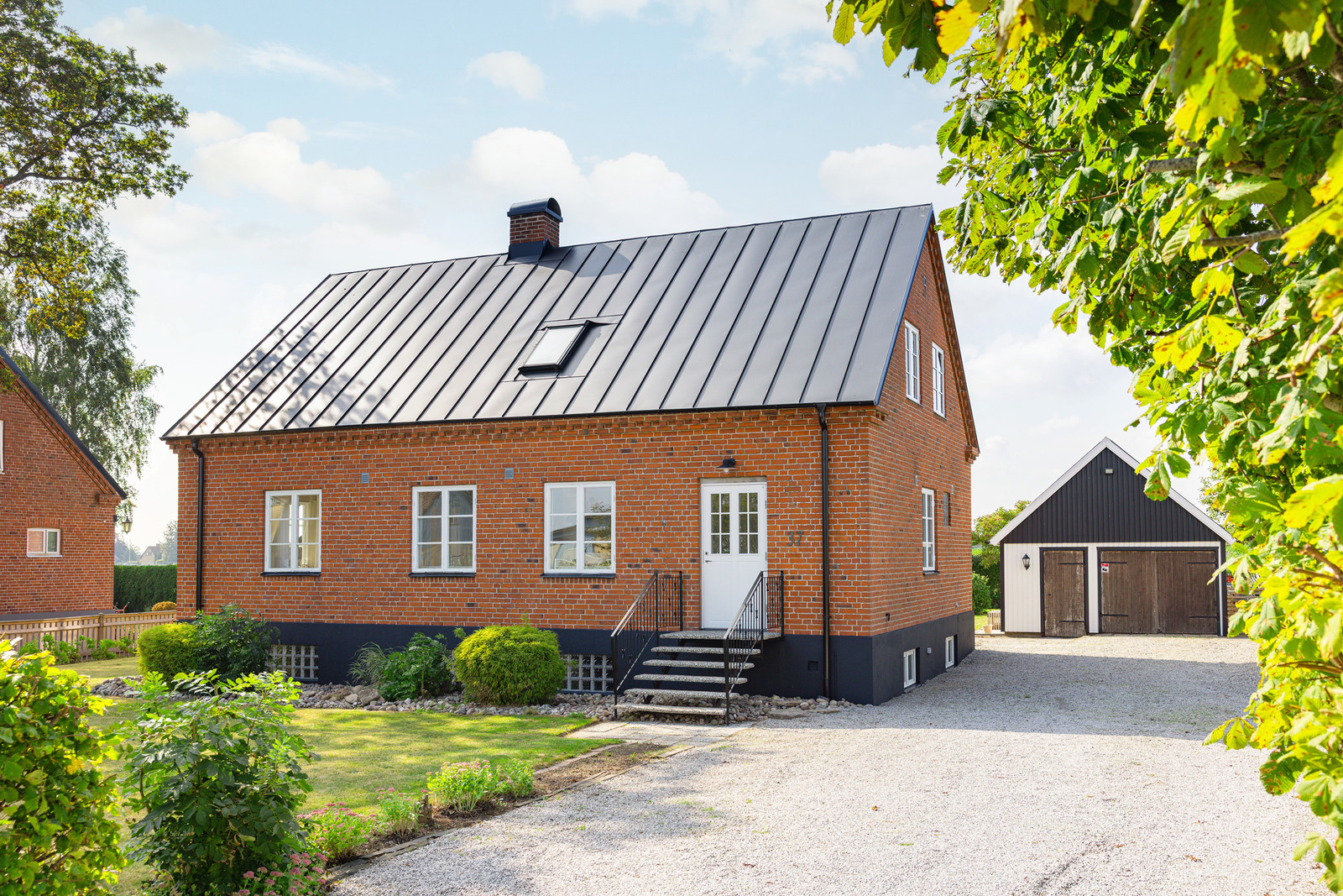 Ståtlig tegelbyggnad med vackert utsmyckad fasad, omvikt takfot och nytt bandtäckt plåttak