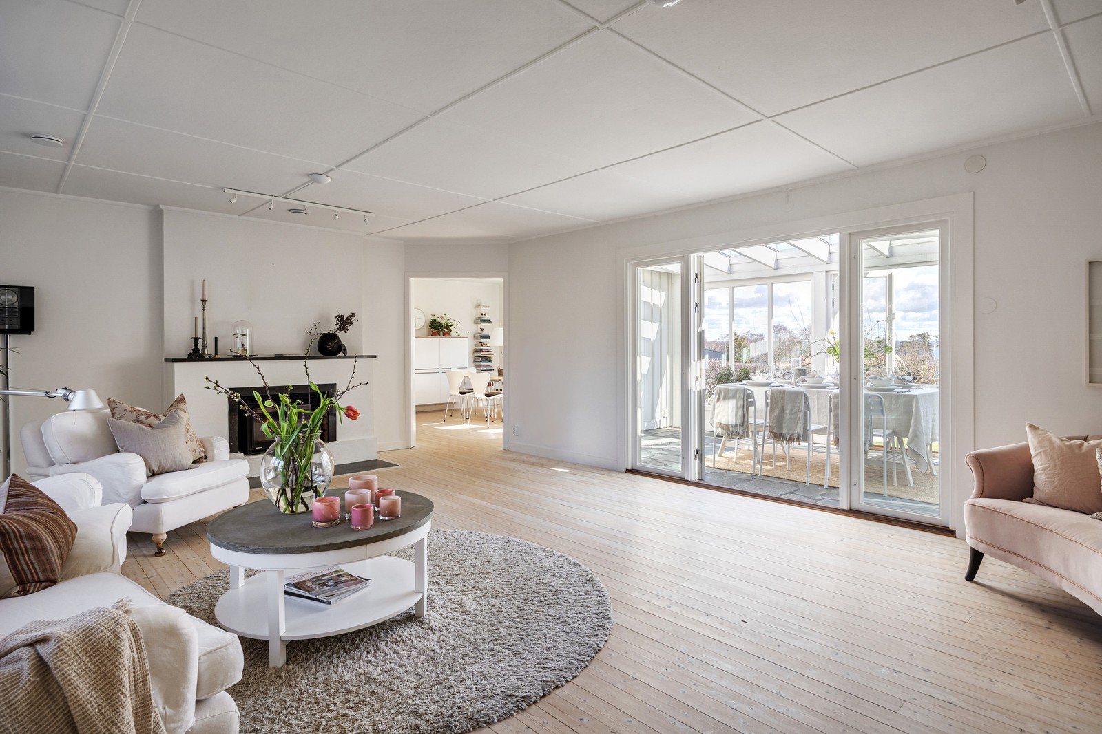 Vackert sällskapsrum med vitsåpade brädgolv och pampig öppen spis