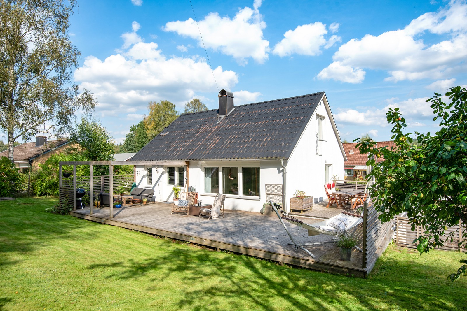 En sommarmorgon skiner solen över den rikt varierade grönskan och faller in över altanen