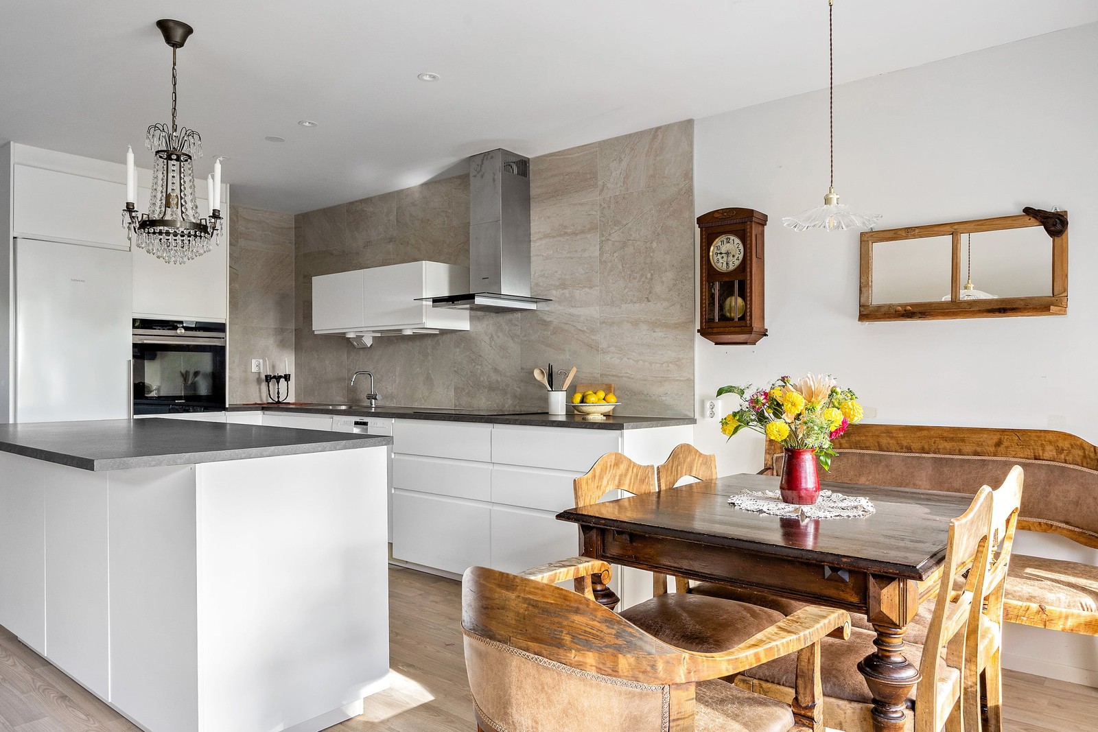 Modernt kök där vita luckor, mörka bänkskivor och naturnära materialval skapar en elegant helhet
