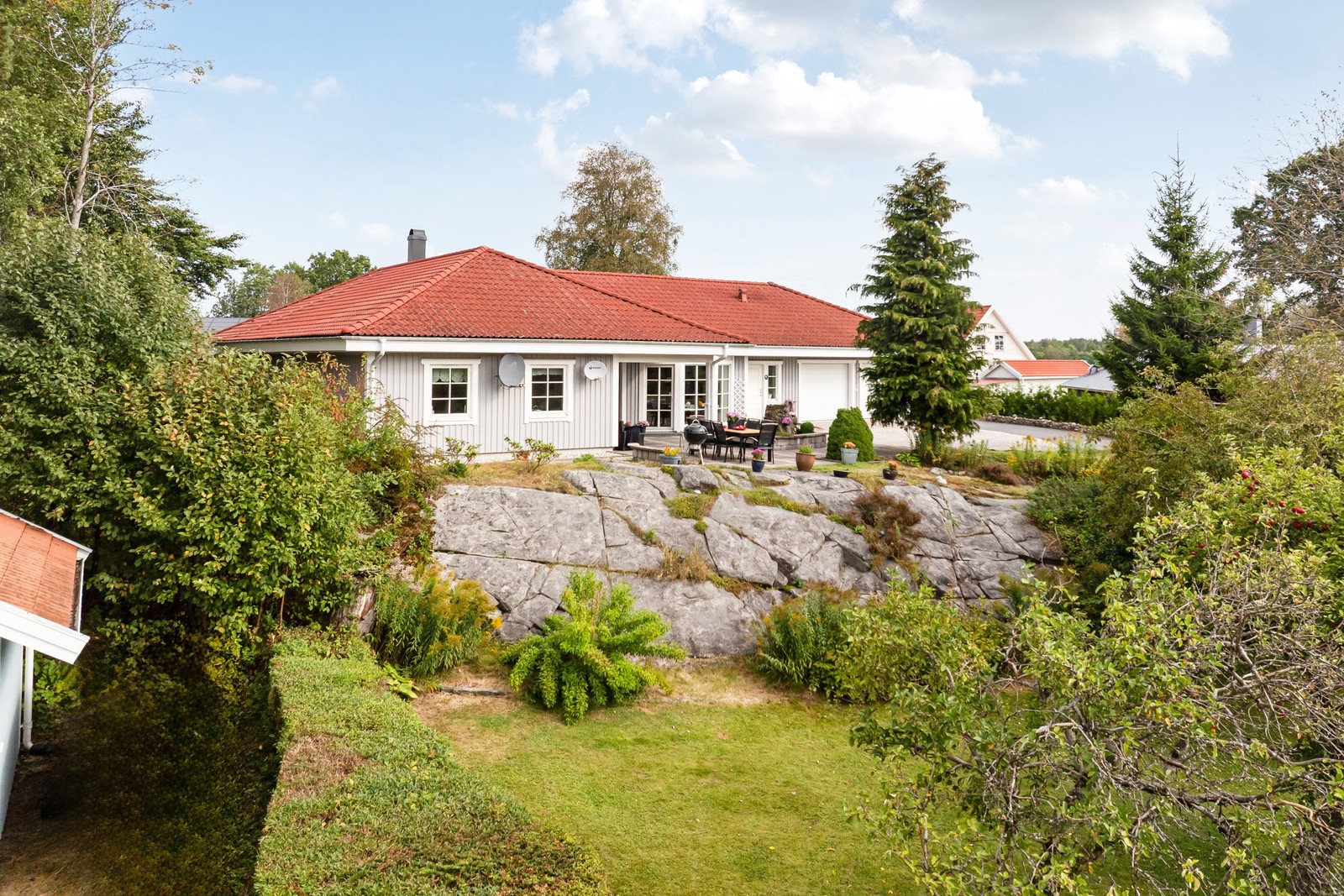 Högt insynsskyddat läge inramat av uppvuxen trädgård och berg i dagen