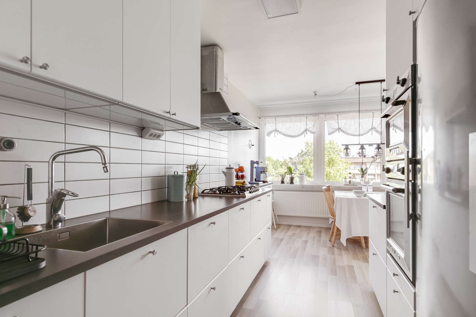 Tidlöst renoverat kök vita skåpluckor, grå bänkar och vitt kakel