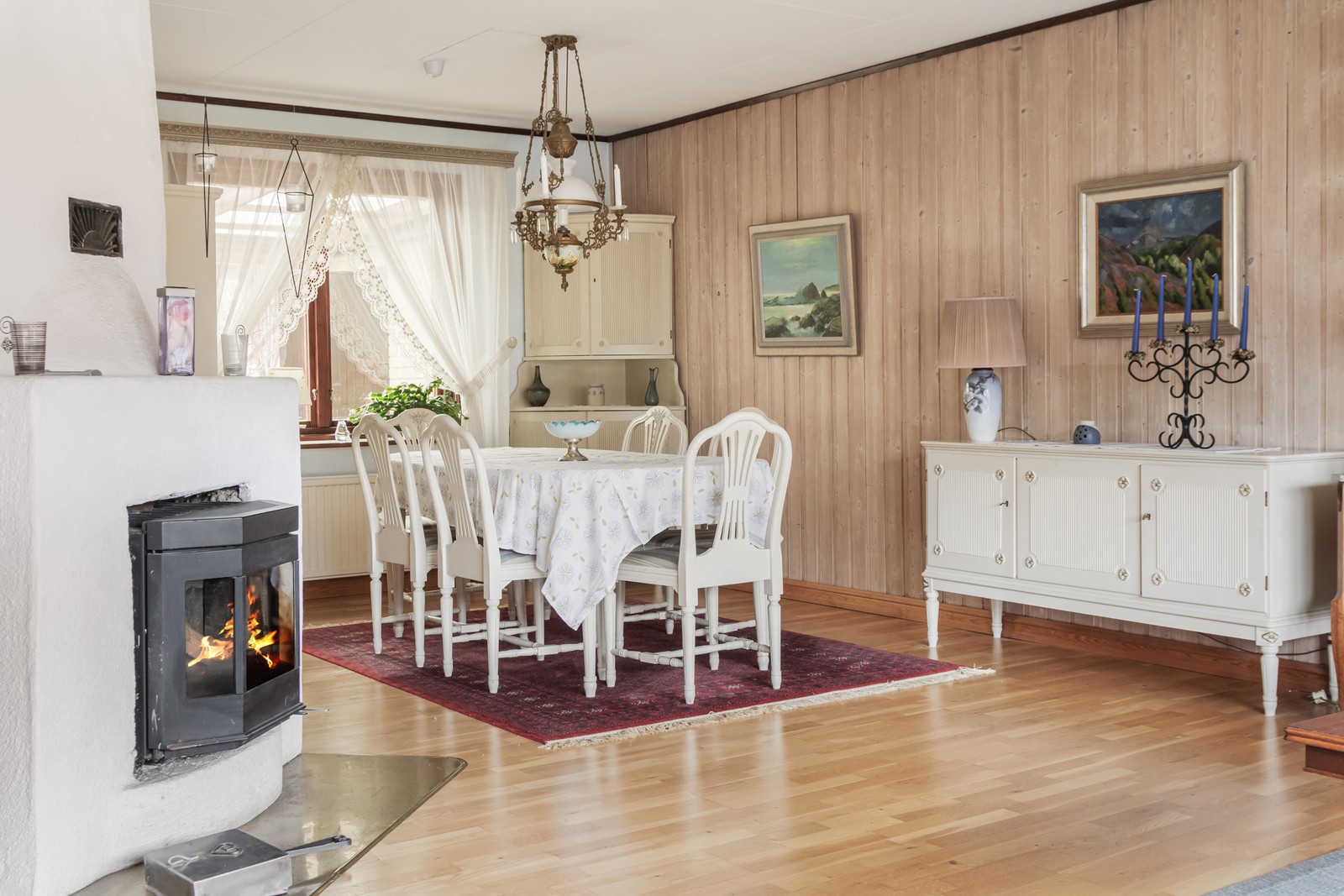 Vinklat vardagsrum med murad eldstad