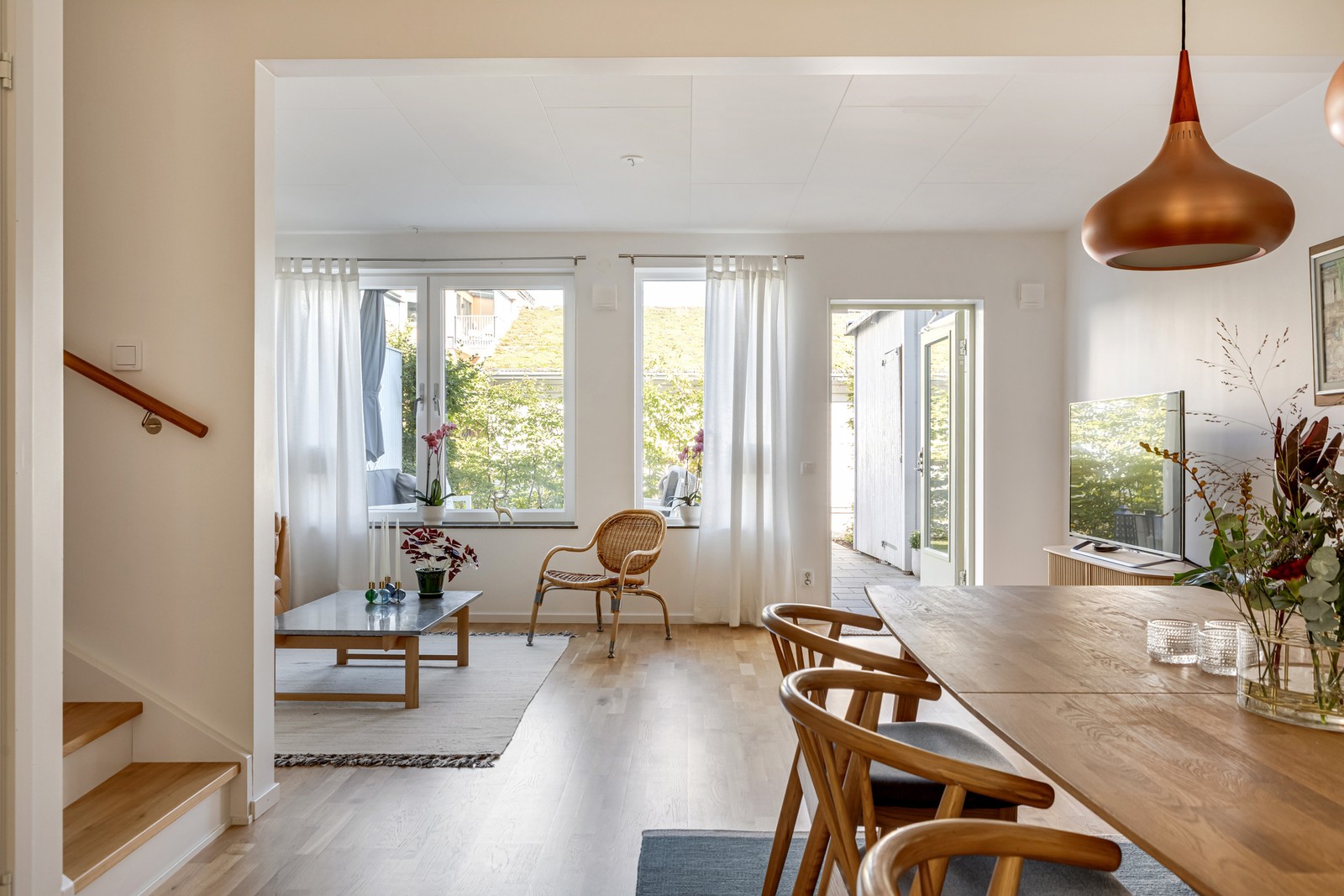 Vy från matplatsen ut mot vardagsrummet med utgång till uteplats och trädgård