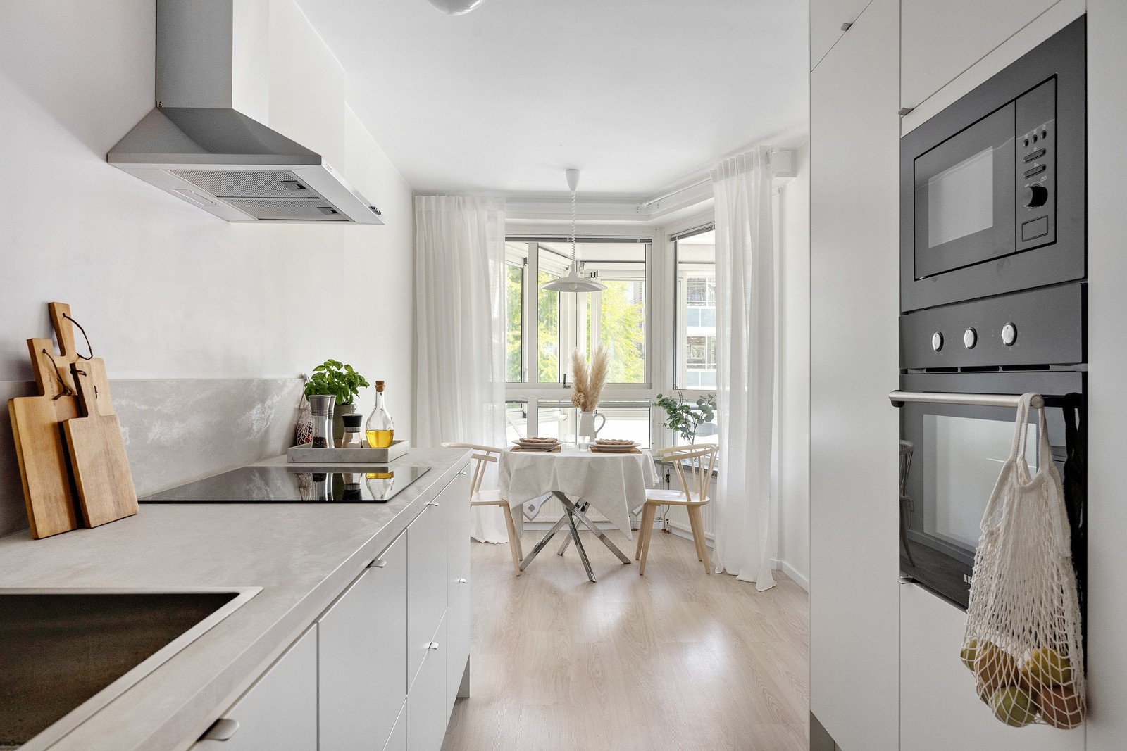 Ljust och modernt kök med gott om arbetsyta och naturlig matplats vid fönstret.
