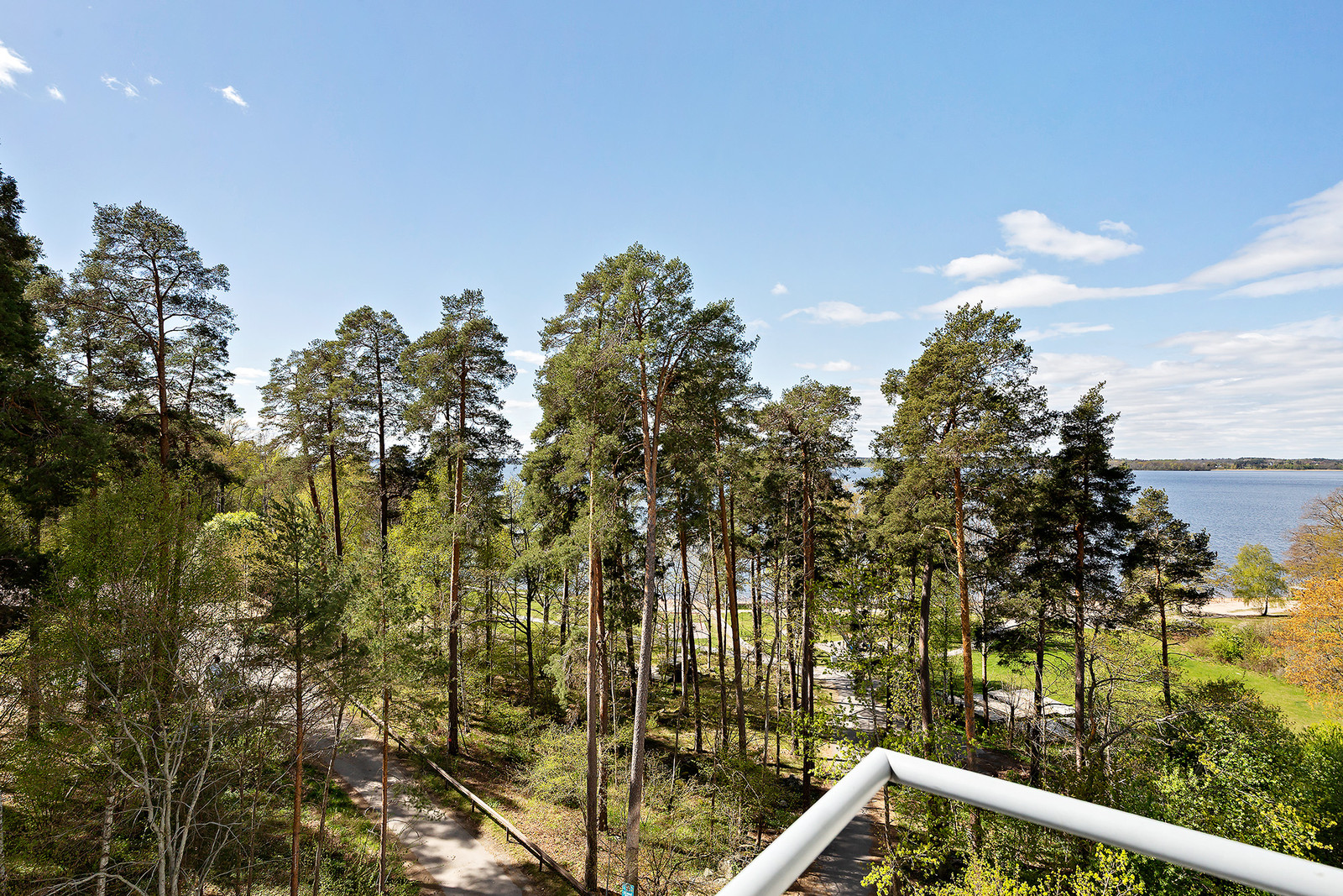 Utsikt mot natur och Mälarens glittrande vatten från balkong