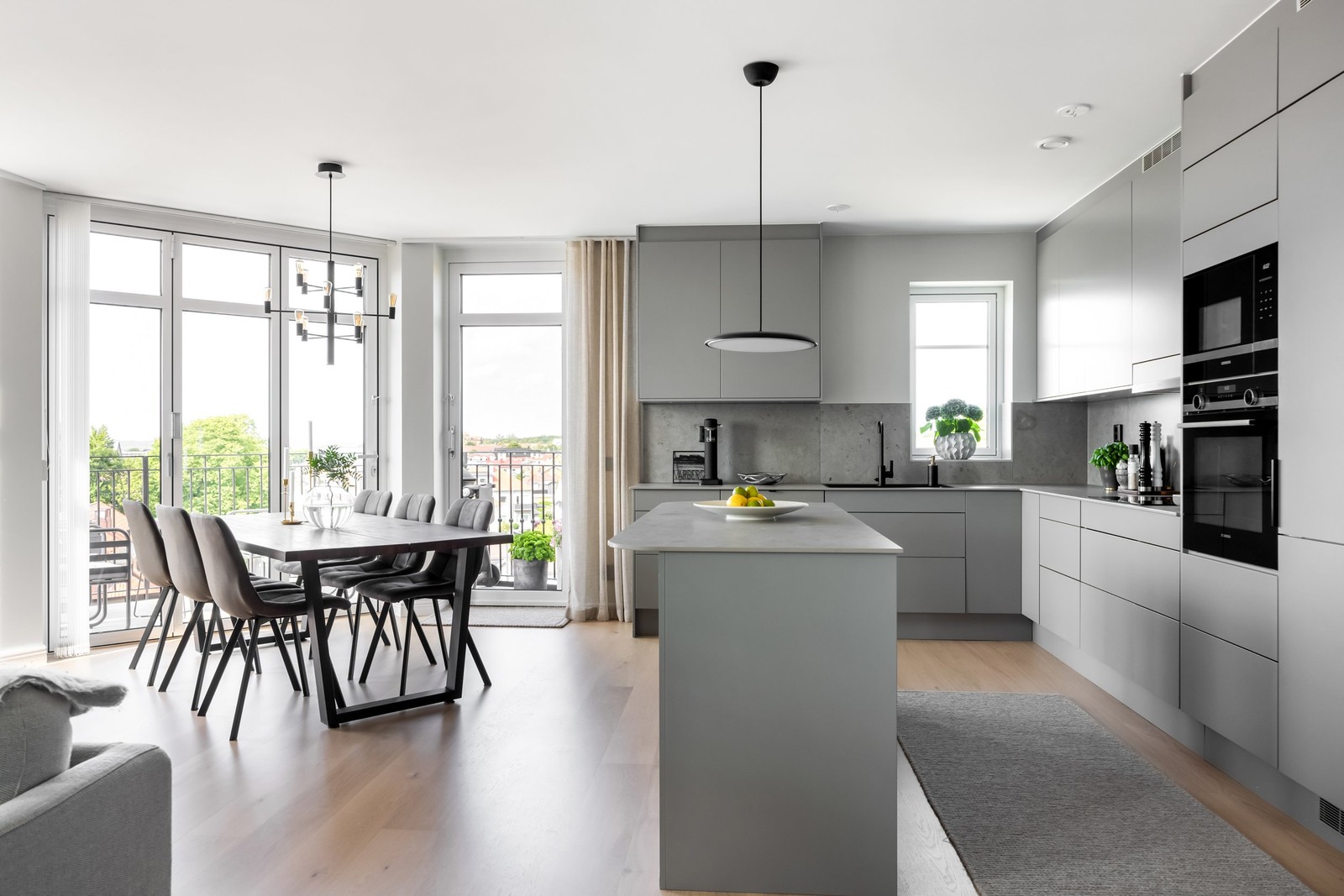 Öppen planlösning mellan kök och vardagsrum med stilren köksö, perfekt för sociala middagar