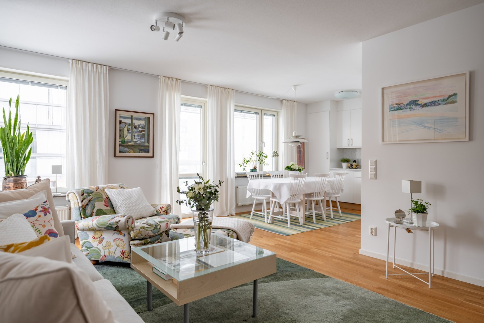 Stort vardagsrum med öppen disposition mot köket och utgång till stor inglasad balkong