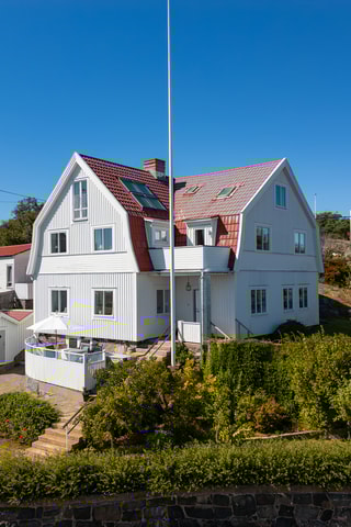 Den vita träfasaden reser sig högt under ett spetsigt och kraftigt brutet tak